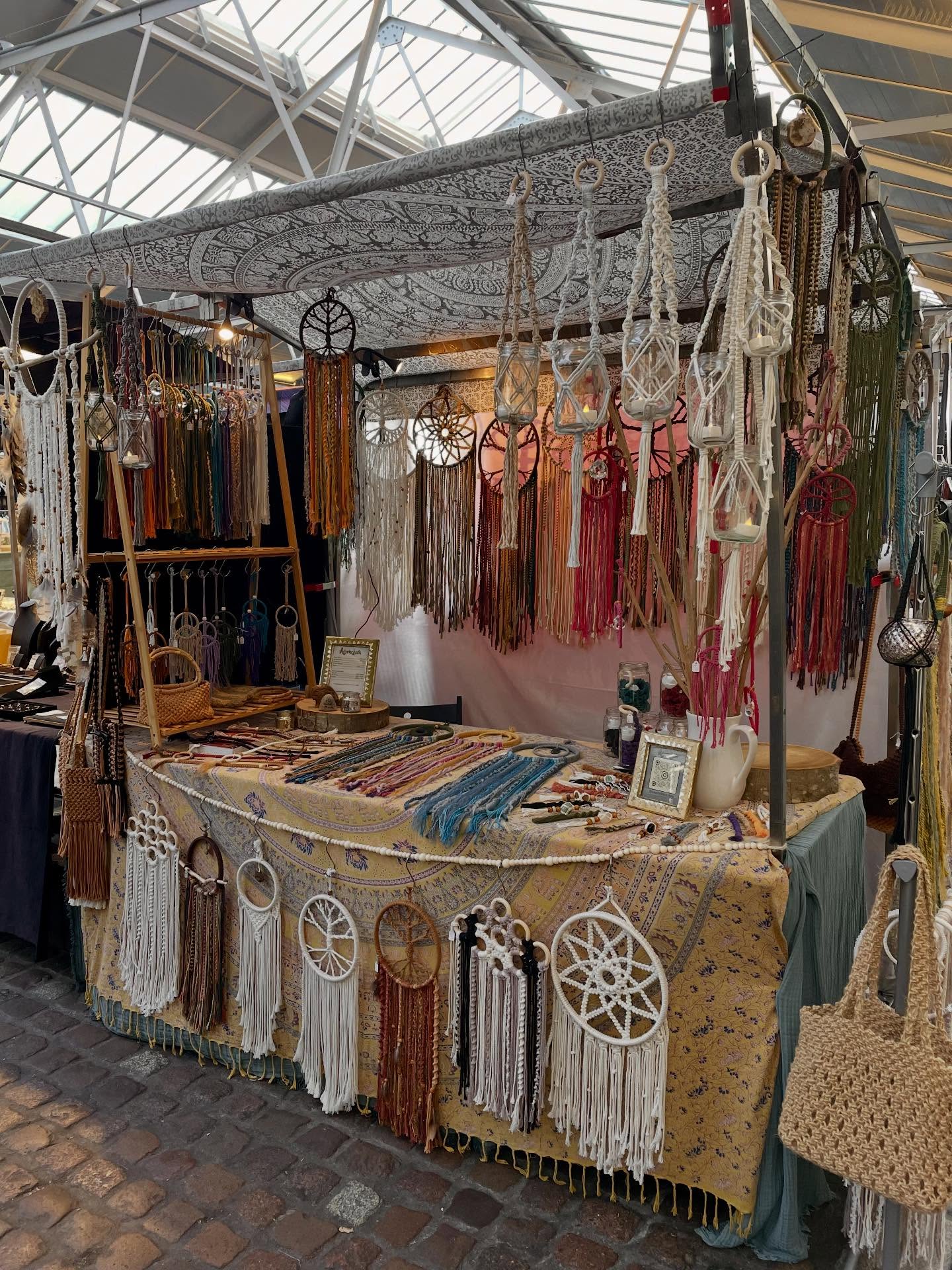 Anamchara market stall with hanging lanterns, wall pieces, and table display