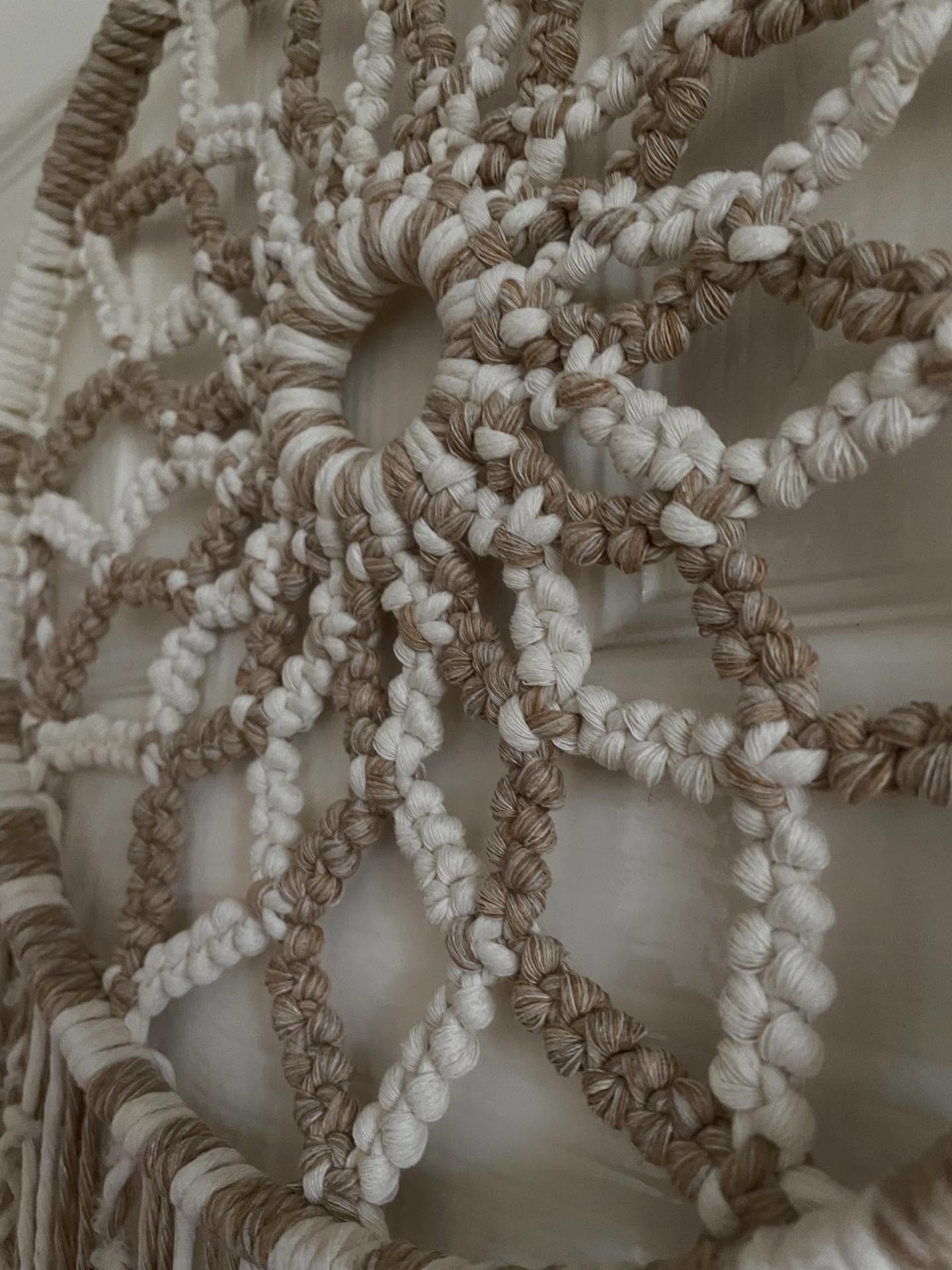 Close-up of a handmade macrame wall piece with mixed fibres and wooden beads